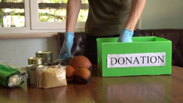 Man loading in donated food into a donation box.
