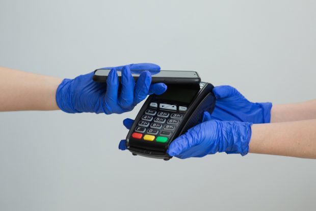 consumer wearing gloves using a smartphone to make a contactless payment.