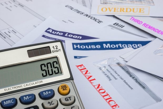 pile of late mortgage payment bills with a calculator that says "S.O.S."