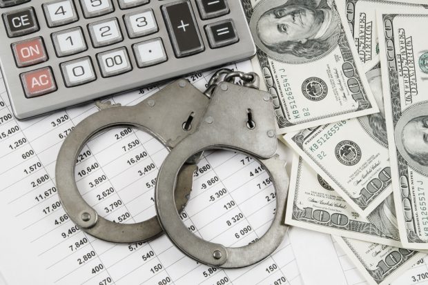 photo of a calculator, handcuffs, cash and a spreadsheet