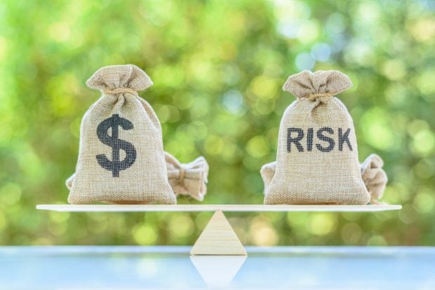 Dollar and risk bags on basic balance scale