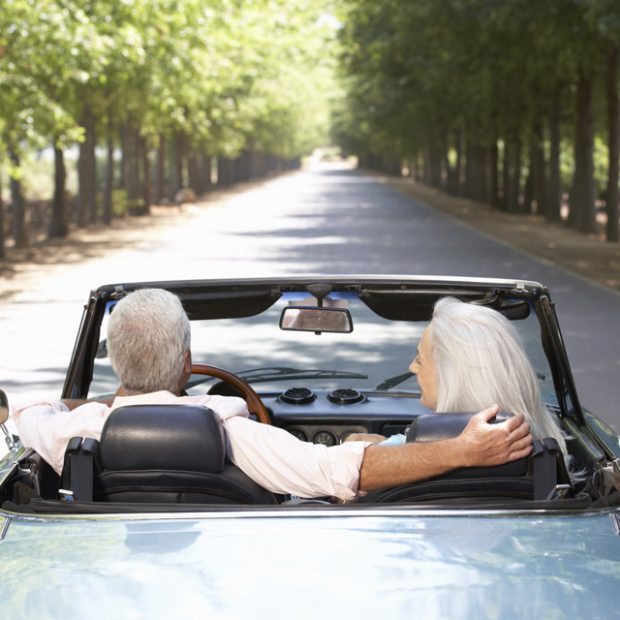 retired couple driving a car into the sunset