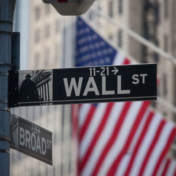 Wall Street sign with the U.S. flag behind it