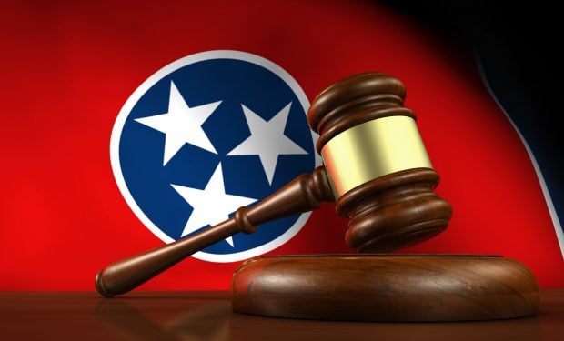 Tennessee state law, legal system and justice concept with a 3d render of a gavel on a wooden desktop and the Tennessean flag on background.