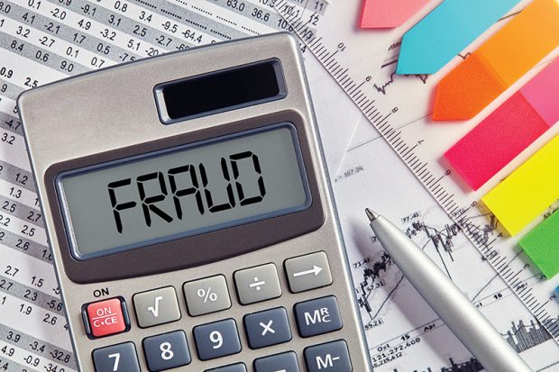 Office desktop with calculator displaying the word fraud. 