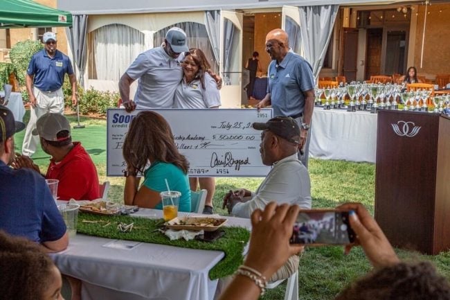 Langgard (standing, center) presents a donation from Sooper CU to the Porter-Billups Leadership Academy (PBLA) at its annual charity golf tournament