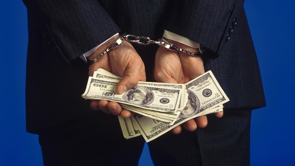 Handcuffed man holding cash.