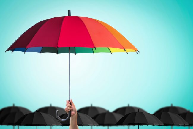 Colorful umbrella covering small black umbrellas