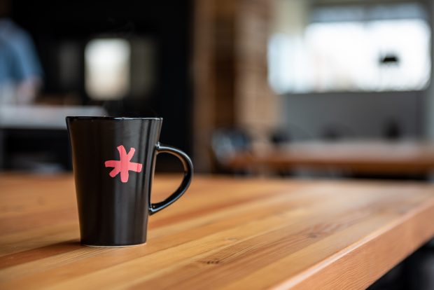 Filene logo on a coffee mug sitting on a long wooden table.