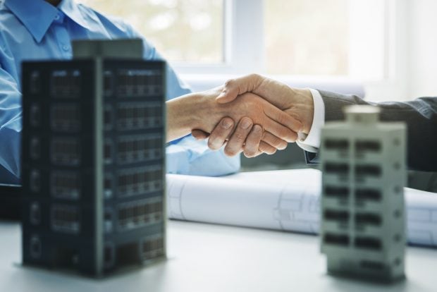 real estate development - businessmen handshake after successful agreement of commercial and apartment building construction project