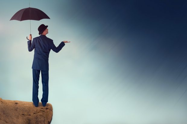 Man with umbrella thinking it is going to rain with dark sky looming