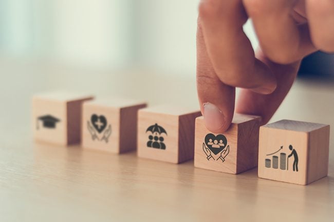 fingers holding blocks representing employee benefits concepts