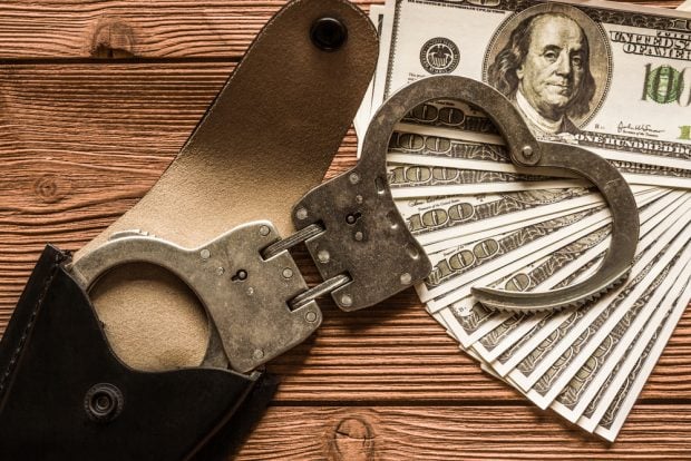 handcuffs sitting on a pile of money