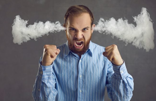 Angry crazy tired bad tempered young office manager or business man feeling pissed off loses control and yells in tantrum venting negative emotions steam coming out of ears isolated on grey background