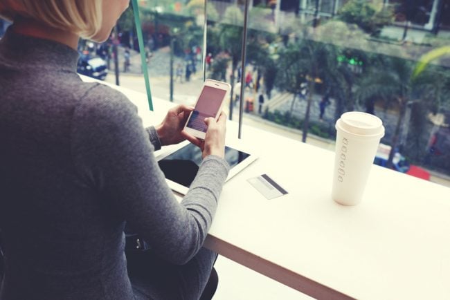 woman using smartphone and tablet in coffee shop