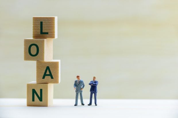 loan spelled out with blocks with two businessmen figures