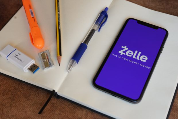 Zelle app open with smartphone sitting on notebook