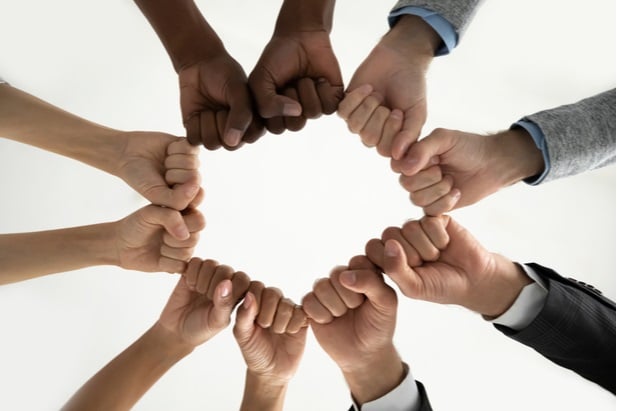 many hands coming together in a circle as fist bumps