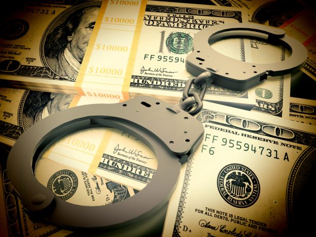 Handcuffs sitting on top of a pile of money.
