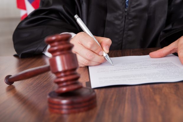 Judge signing a sentence order with a gavel sitting nearby