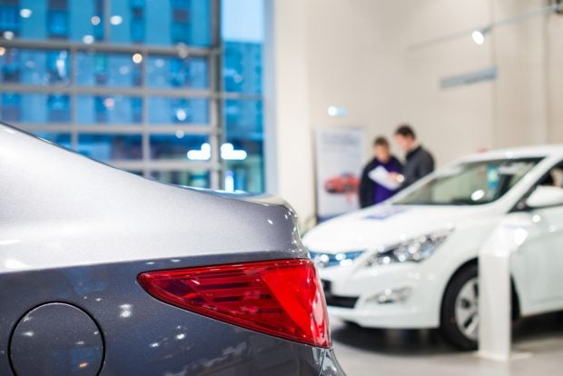 Auto showroom with two people looking at new cars.