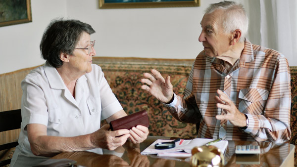 Elderly couple sitting at a table discussing finances.