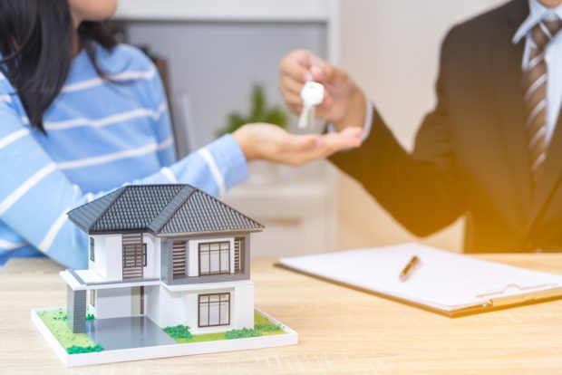 lender handing person a key to their home after securiing a home loan
