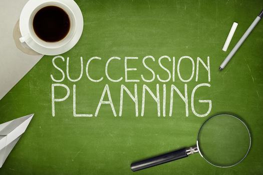 "succession planning" written on chalkboard with coffee and magnifying glass