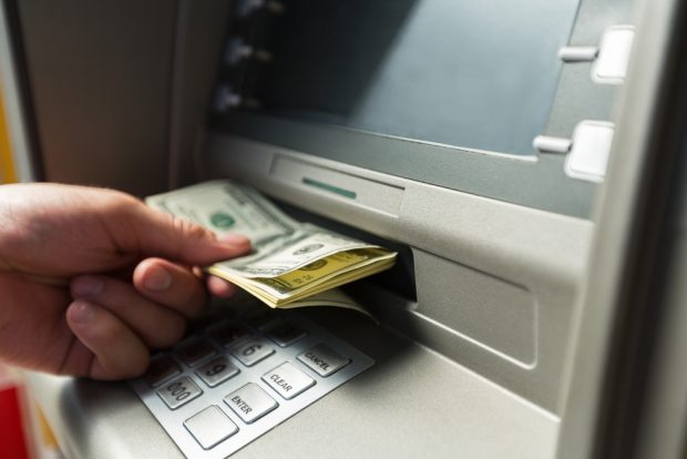 A hand pulling money out of an ATM.