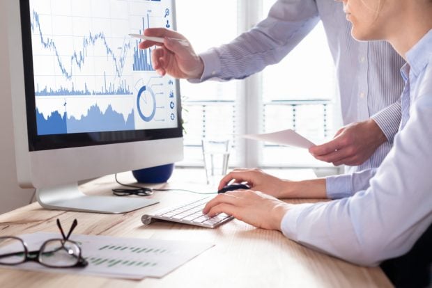 two employees reviewing data on a computer screen