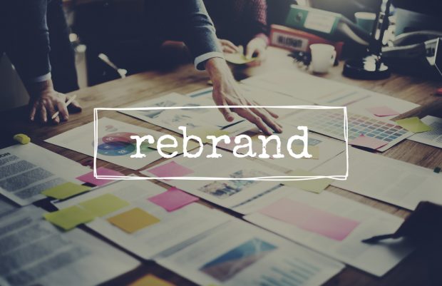executives reviewing paperwork on table with "rebrand" word overlay
