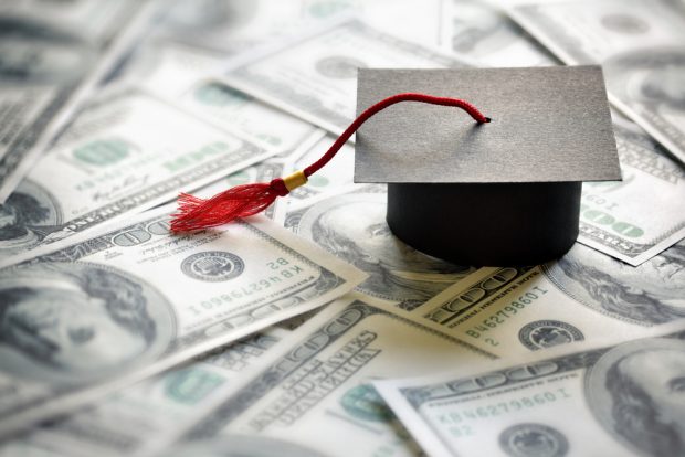 Graduation cap sitting on top of a pile of money.