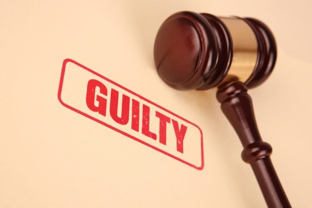 Guilty stamped in red letters on a legal folder with a gavel sitting nearby