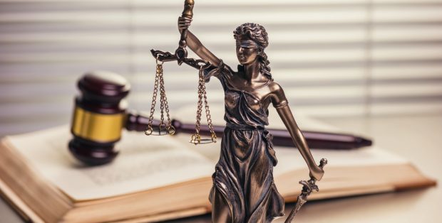 statue of lady justice next to a gavel and law books