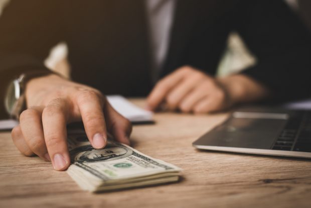 Man slides stack of cash across desk to member.