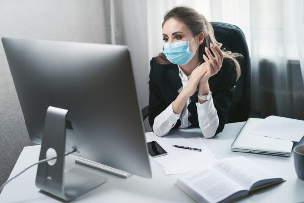 Masked employee sitting at her desk