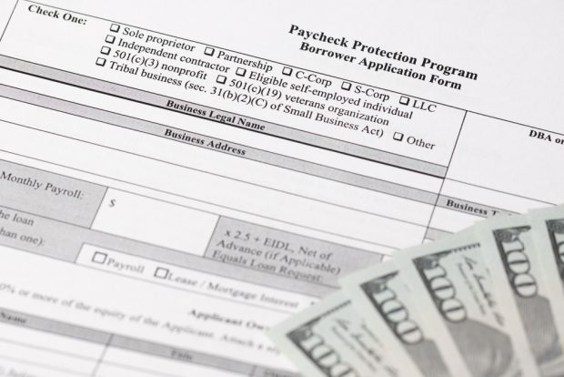 Paycheck Protection Program application with a stack of cash.