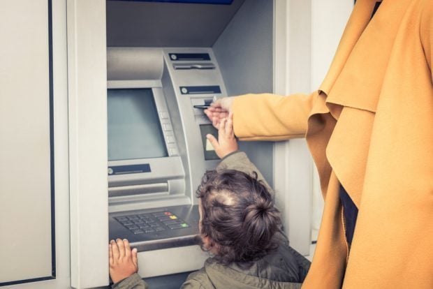 small child helping parent at the ATM