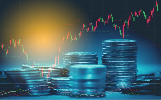 stacks of coins in front of an up and down economic chart