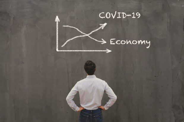 man looking at a chart showing growth of COVID 19 and a decline in the economy