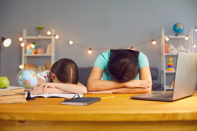 Mother and daughter with heads down on home office desk