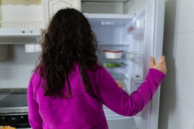 woman looking into an empty refrigerator