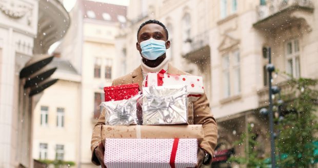 Man wearing a face mask holding holiday packages.
