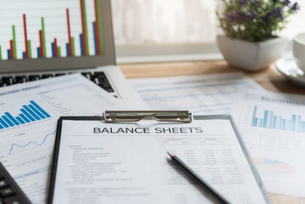 balance sheet on a clipboard with a pen