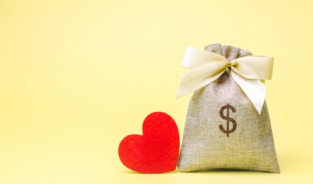 Valentine's heart sitting next to a bag of money.