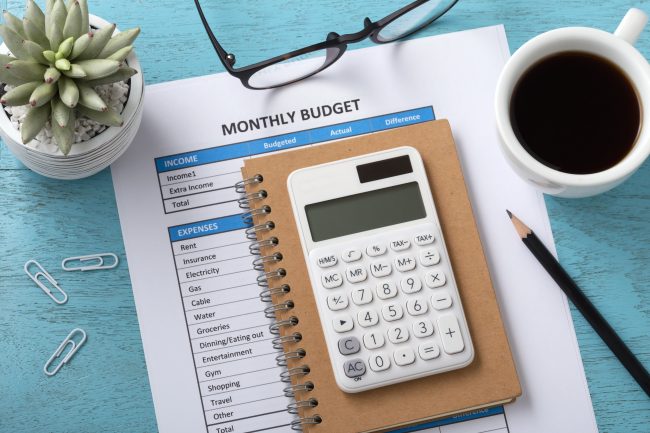 Monthly budget concept with white calculator and coffee cup on blue wooden table