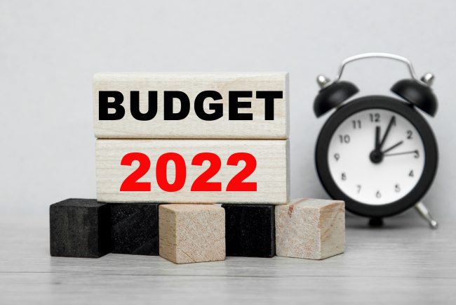 The words budget 2022 written on wooden cubes with an alarm clock .