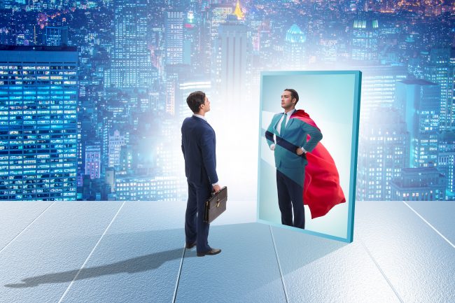 businessman seeing himself in mirror as superhero