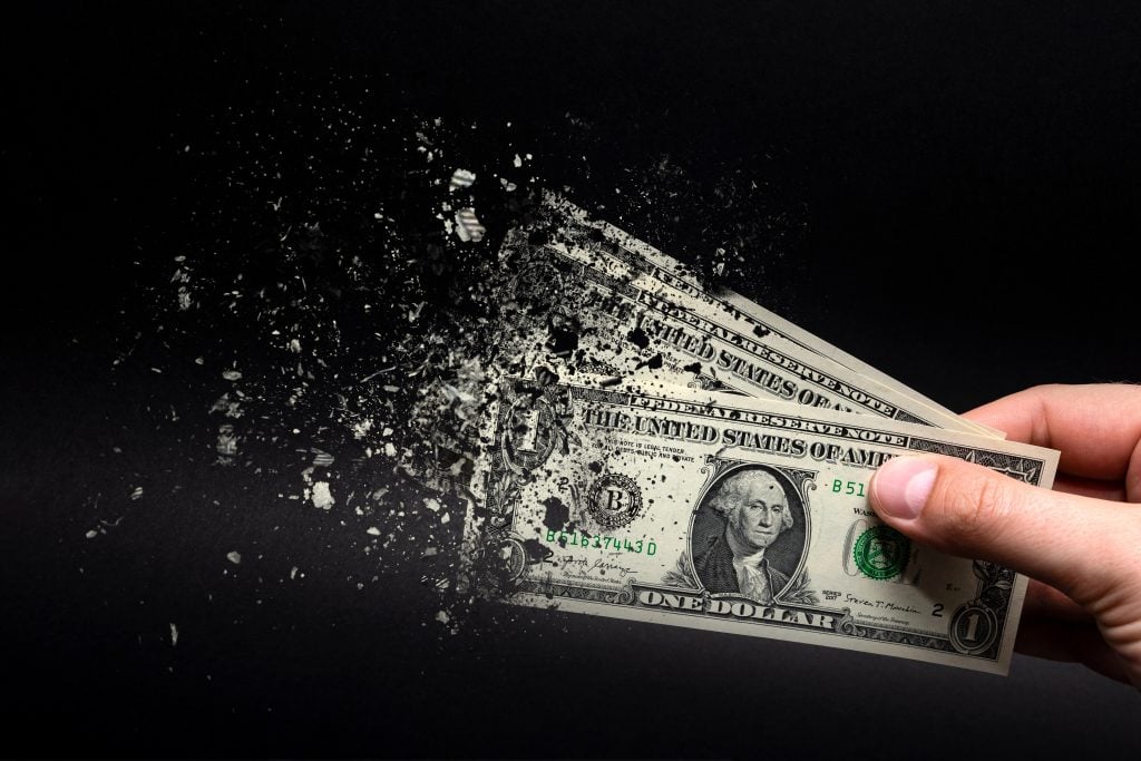 Inflation, dollar hyperinflation with black background. One dollar bill is sprayed in the hand of a man on a black background. The concept of decreasing purchasing power, inflation