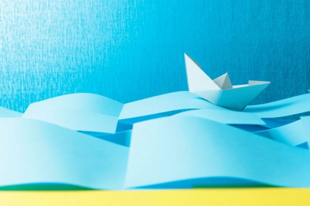 A white paper boat on a blue paper sea.